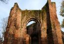 The red brick walls and archway of the ruins of St John's Church in Chester'