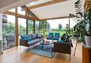 The Velfac double doors in the oak-framed garden room are in frameless glass in oak poster beams. The lighting was designed by Lightmaster Direct, and the roof lights are from the Rooflight Company. The coffee table is from Made, with sofas from Heals