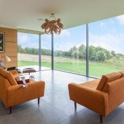 Sliding doors at rights angles open in the corner. The bentwood light fitting is by Tom Raffield, and the sofas are from eBay, originally yellow but now recovered in an orange fabric