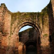 The red brick walls and archway of the ruins of St John's Church in Chester'