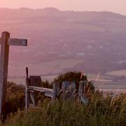 View fromSouth Downs Way marker post near Firle Beacon across to Swanborough Hill in the west, at sunset.