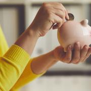 Woman inserts a coin into a piggy bank, toned image