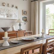 Dining Room: the table and chairs came from Heals via  auction and cost Sarah £2,000.  The sideboard beyond is a 1970s Gordon Russell piece and the paper seascape above was made by Rebecca when aged 16. The pottery on the frame above it was made by