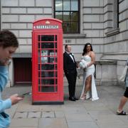 A newly married couple have their picture taken beside a red phone box at Parliament Square in Westminster