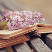 Lilac branch with a tape on the old book on a bench..