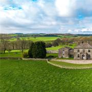 An aerial view of the property set within its own grounds, surrounded by open green fields and rolling countryside