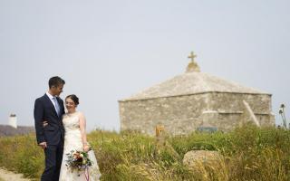 Bride and groom with their memorable Dorset wedding location, the 12th century St Adlhelm's chapel. (Photo: Tim Churchill Photography/sunflowerco.co.uk)
